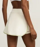 Short pollera deportivo de microfibra color blanco hueso, con cintura alta y bies contrastante en el ruedo.
