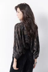 Camisa marrón con estampado abstracto en tonos cobre y negro, cuello mao y mangas largas abullonadas con puños elásticos.