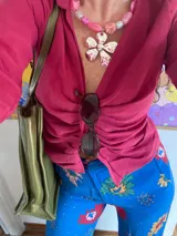 Collar con dije metálico de flor y mostacillas rosadas variadas.