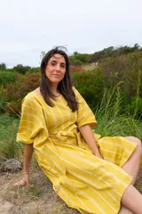 Vestido túnica amarillo con rayas verticales blancas, corte amplio, mangas cortas y lazo para ajustar en la cintura.