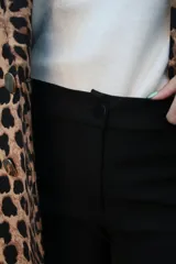 Pantalón negro de vestir, de tiro medio con elastano, corte recto y bolsillos laterales.