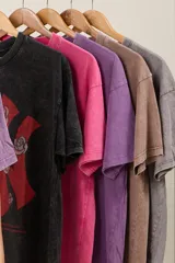 Remera oversize color lila con estampado de una letra K roja con rosas y un diseño abstracto.