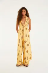 Mono largo amarillo con estampado de conchas, escote halter con lazo y corte holgado.