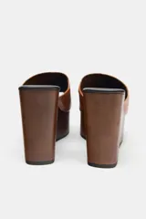 Sandalias de cuña color marrón con tira ancha de cuero sintético y plataforma de madera.