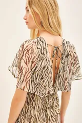 Vestido largo de viscosa jacquard con estampado de cebra en tonos marrón y negro, con detalles de lurex dorado. Presenta escote en V cruzado, elástico en la cintura y mangas cortas con volados.