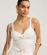 Top cropped blanco de tirantes anchos, confeccionado en tejido de punto texturizado, con escote en V y detalle de nudo o torcido en el centro del busto.