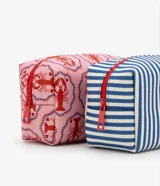 Set de tres neceseres: uno grande transparente con ribetes rojos y dos rectangulares internos. Uno rectangular tiene estampado de rayas verticales azules y blancas, y el otro tiene estampado de langostas rojas sobre fondo rosado.