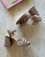 Sandalias color beige con plataforma y taco cuadrado, tiras cruzadas sobre el empeine y pulsera al tobillo con hebilla dorada. Fabricadas en cuero vacuno. Taco de 9cm.