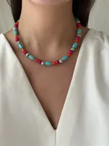 Collar corto de cuentas de colores: turquesa, fucsia, naranja y blanco con manchas negras.