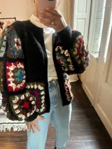 Saco negro de tejido de punto con mangas abullonadas de crochet con diseño de cuadrados de colores.
