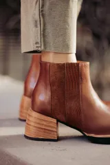 Bota de cuero marrón con texturas en los laterales y taco medio, ideal para el uso diario.