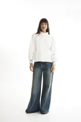 Camisa blanca de estilo romántico con cuello alto, mangas largas abullonadas y detalles de broderie.