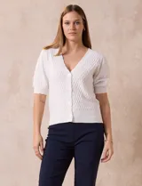 Cárdigan tejido color blanco, marca Tahari. Escote en V, manga corta abullonada con puño y abertura central con botones.