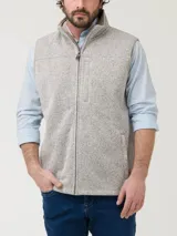 Chaleco de polar color beige jaspeado, con cuello alto y cierre frontal. Tiene tres bolsillos frontales con cierre.