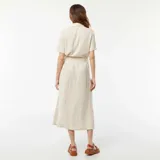 Vestido largo color beige, estilo camisero, con cuello clásico, mangas cortas, abotonadura frontal y lazo en la cintura.