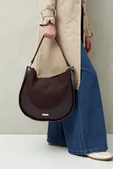 Bolso tipo hobo de cuero sintético negro con panel frontal de gamuza. Tiene correa de hombro ajustable y logo metálico plateado.