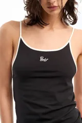 Musculosa negra de jersey de algodón con modal peruano, de calce fitted, escote en "U" y largo a la cadera. Presenta detalle de breteles y escote a contratono en blanco. Cuenta con bordado marcario a contratono en frente como distintivo.