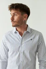 Camisa de hombre a rayas verticales celestes y blancas, corte slim fit, manga larga, logo bordado en el pecho y cartera con botones.