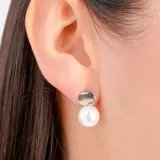 Aros colgantes con un círculo plateado y una perla blanca.