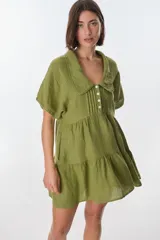 Vestido corto celeste de lino, con cuello tipo polo con detalle de puntilla, mangas cortas y falda escalonada con volantes.