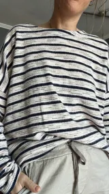 Sweater tejido de punto a rayas horizontales color crudo y azul marino, de corte holgado y mangas largas.