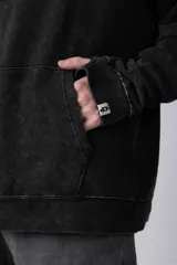 Buzo canguro verde con efecto desgastado, capucha con cordón ajustable, bolsillo frontal y puños con orificio para el pulgar.