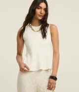 Blusa sin mangas color blanco, confeccionada en punto roma, con cuello redondo y corte peplum.