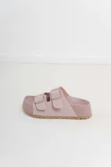 Sandalias color rosa con doble hebilla ajustable y suela marrón.