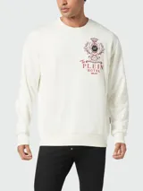 Buzo de cuello redondo color crema o blanco roto, de manga larga y corte regular. Presenta un estampado frontal en color rojo oscuro que simula un escudo heráldico con el texto "The PLEIN HOTEL MILAN".