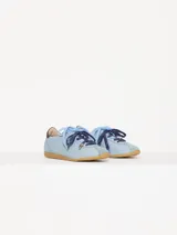 Zapatilla de cuero marrón con detalles en verde y suela de goma. Tiene cordones rosas y un dije colgante con forma de abeja.