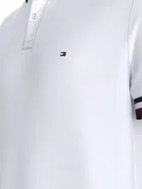 Chomba blanca de algodón orgánico con cuello polo a rayas azul marino y rojo. Tiene cartera de dos botones y logo bordado en el pecho.