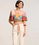 Pantalón mom color crudo confeccionado en sarga de algodón BCI, con bolsillos delanteros y traseros, cierre con botón y cremallera, y pañuelo estampado a modo de cinturón.