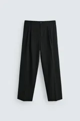 Pantalón negro de corte ancho, con cintura elástica, pliegues frontales, bolsillos laterales y traseros de ojal. Cierre frontal con cremallera y botón.