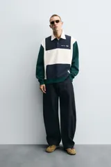 Polo de manga larga con corte relaxed fit, confeccionado en tejido con algodón. Presenta un diseño color block en azul marino, blanco y verde, con cuello solapa con cierre frontal de botonadura. Cuenta con bordados y parches combinados a contraste en delantero y espalda, y acabados en rib.