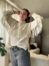 Sweater de lana color crema, con cuello redondo y mangas largas. Presenta una banda horizontal de flecos en el pecho.