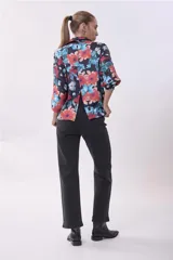 Camisa de mangas 3/4 con estampado floral en tonos naranja, celeste y verde sobre fondo negro.