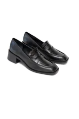 Zapato tipo mocasín color negro charol con relieve de cocodrilo, punta cuadrada y tacón bajo.