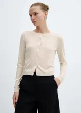 Cárdigan de punto fino color crema, con cuello redondo, manga larga y cierre frontal con botones.
