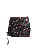 Minifalda negra con estampado de calaveras, labios, zapatillas, auriculares y la frase 'Rock'n'Roll' en blanco y rojo. Tiene cintura elástica y cordones laterales ajustables.