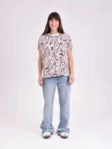 Remera blanca con estampado abstracto en tonos violeta, rosa y celeste.