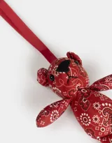 Llavero con forma de oso de peluche rojo con estampado paisley y cinta de agarre roja.