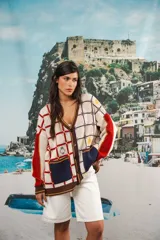 Cardigan oversized de tejido jacquard color crema con diseño de cuadrados en marrón y detalles bordados. Tiene cuello en V, cierre con botones, mangas largas y bolsillos frontales.