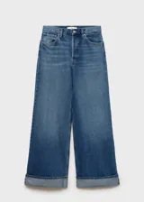 Pantalón de jean azul de corte wide leg, tiro medio, con cierre de cremallera y botón, bajo con dobladillo y cinco bolsillos.