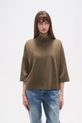 Polera holgada de poliéster color verde militar, con cuello alto tipo tortuga y mangas tres cuartos.