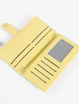 Billetera larga de cuero vegano color amarillo, con textura granulada, cierre con broche a presión y cierre de cremallera superior.