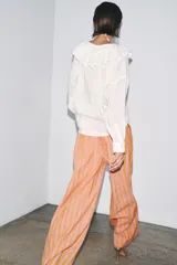 Pantalón de pierna ancha confeccionado en mezcla de lino a rayas verticales color rosa y beige. Tiene tiro medio, cintura elástica y bolsillos delanteros.