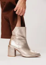 Bota de caña media color champagne de cuero, con horma redonda, taco cuadrado y pequeña plataforma. Cuenta con cierre del lado interno.