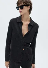 Camisa negra de tejido de lúrex con cierre de botones en la parte delantera, cuello camisero y manga larga.