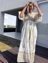 Vestido túnica largo color crudo con estampado de arabescos dorados, escote en V y mangas cortas amplias.