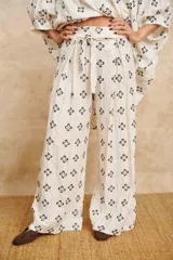 Pantalón palazzo color crudo con bordado de flores negras y cinto de la misma tela.